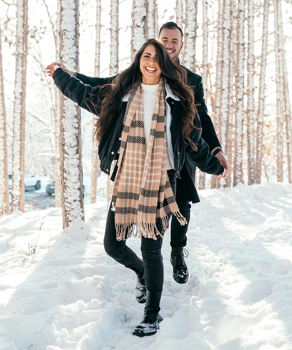 Happy couple walking through a snowy forest
