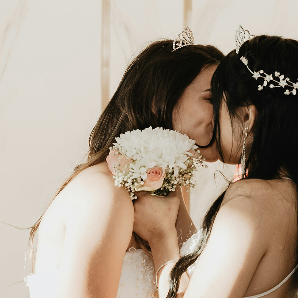 Two brides kissing with a bouquet